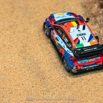 Carro de brinquedo de rali colorido com vários logótipos e número 11 na areia