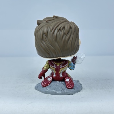 Figurina Funko Pop com fato vermelho e dourado sentado numa base cinza
