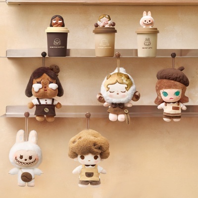 Canecas com bonecos no topo e peluches pendurados em ganchos numa parede bege