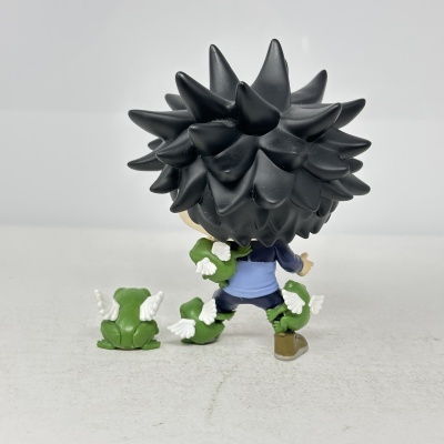 Figura colecionável de personagem com cabelo preto espetado e pequenas rãs verdes com asas