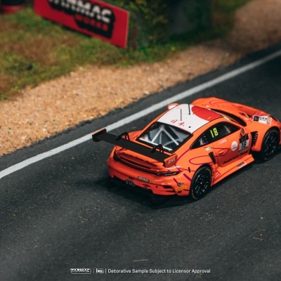 Miniatura de carro desportivo laranja número 18 numa pista de corrida com detalhes das laterais e relva adjacente.