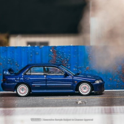 Carro desportivo azul metálico em miniatura com rodas brancas junto a muro azul