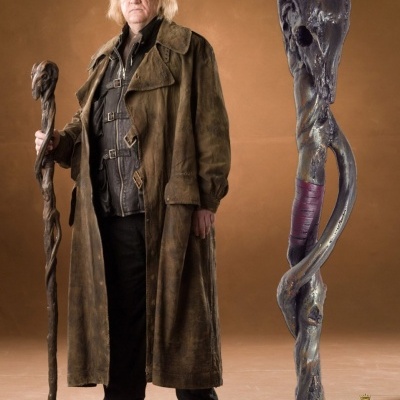 Bengala retorcida escura com detalhe vermelho segurada por pessoa com casaco castanho.