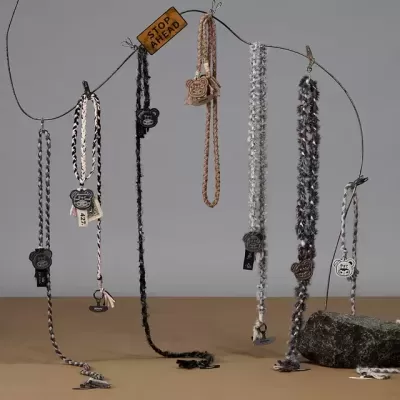 Coleiras trançadas com etiquetas de urso penduradas em suporte com placa STOP AHEAD