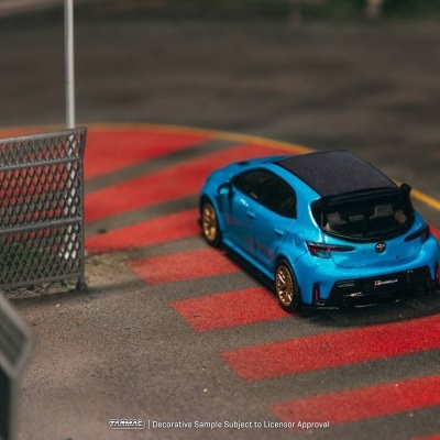 Miniatura de carro azul metálico Toyota Corolla em superfície com faixas vermelhas