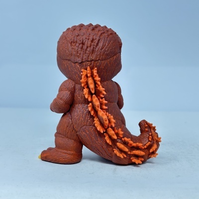 Boneco de plástico castanho com textura rugosa e espinhos alaranjados na coluna