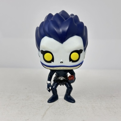 Figura colecionável com cabelo azul, olhos amarelos e segurando uma maçã.