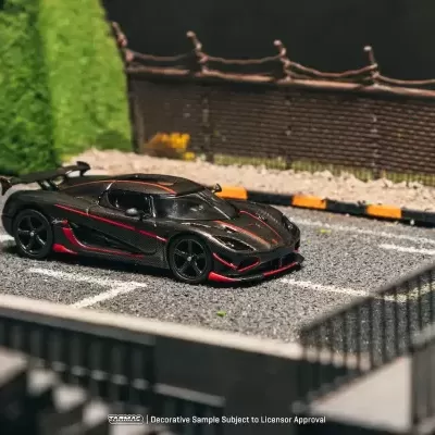 Miniatura de carro desportivo preto com detalhes vermelhos numa estrada em miniatura.