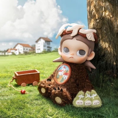 Boneco de pelúcia com corpo macio castanho e decorações brancas sentado perto de uma árvore e um carrinho de madeira