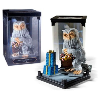 Figura de criatura mágica cinzenta segurando doces e presentes numa base preta com embalagem ao fundo