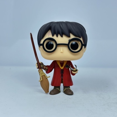 Funko Pop de Harry Potter com capa vermelha, óculos pretos, segurando vassoura e objeto dourado