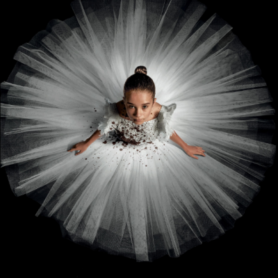 Menina de vestido branco visto de cima com texto vermelho em fundo preto