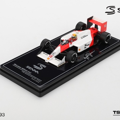Miniatura do carro de Fórmula 1 McLaren MP4/4 com base preta e texto sobre Ayrton Senna.