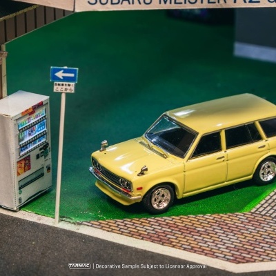 Modelo reduzido de carrinha amarela junto a máquina de vending e placa de sinalização