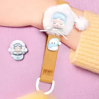 Pulseira castanha com broches temáticos azul e branco sobre manga amarela e fundo roxo