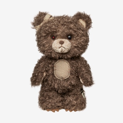 Ursinho de peluche castanho encaracolado com manchas de tecido cru e olhos de botão