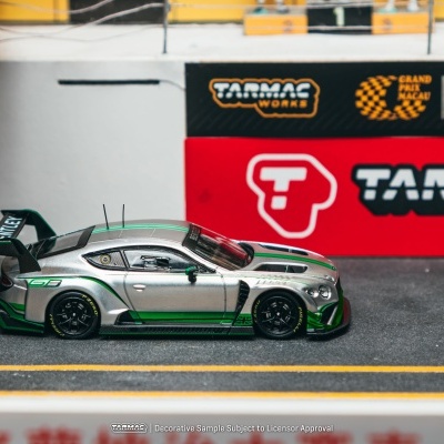 Miniatura prata e verde de carro desportivo com painéis publicitários ao fundo