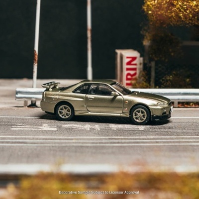 Modelo de carro desportivo metálico dourado numa rua com linhas brancas e vedação metálica