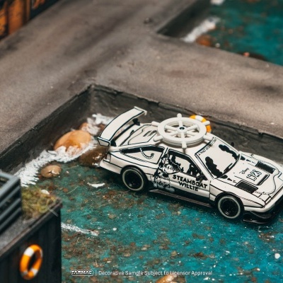 Carro de brinquedo Steamboat Willie branco com volante de navio no teto numa miniatura de cenário com água e pedras