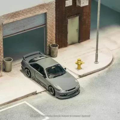 Miniatura de carro desportivo cinzento estacionado numa rua com candeeiro de rua