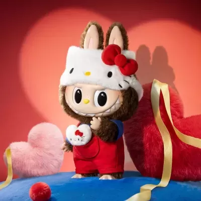 Figura de peluche com chapéu e roupa colorida sobre suporte azul com corações ao fundo
