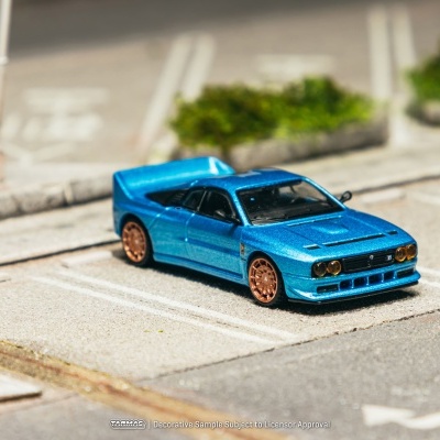 Miniatura de carro desportivo azul metálico com jantes douradas num estacionamento