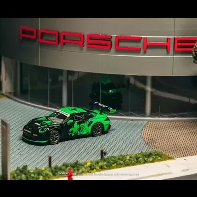 Miniatura de carro verde e preto com dragão em frente a loja Porsche