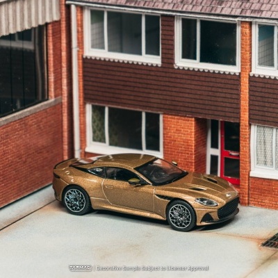Modelo em miniatura de carro desportivo dourado junto a edifício de tijolo