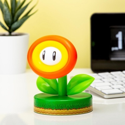 Figura de flor estilizada colorida em plástico sobre mesa branca com teclado e planta