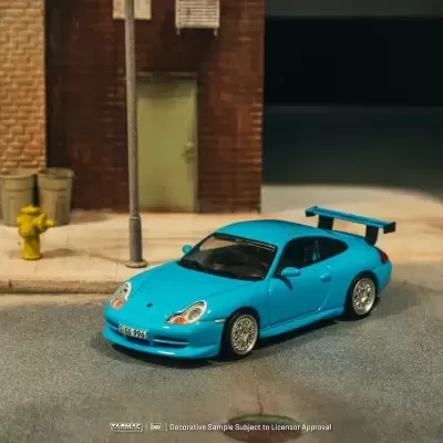 Miniatura de carro desportivo azul com asa traseira e detalhes visíveis num cenário urbano em miniatura