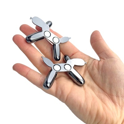 Mão a segurar dois massajadores de metal cromado com duas bolas circulares.