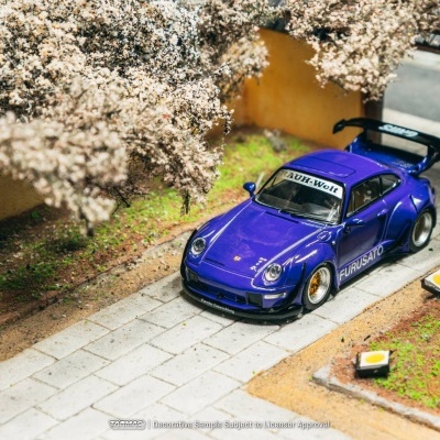Miniatura de carro desportivo azul numa estrada com árvores floridas