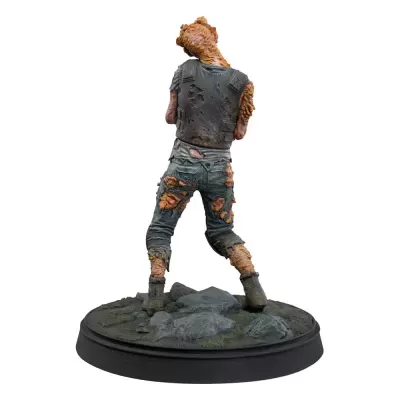 Figura colecionável de zumbi com roupas rasgadas numa base rochosa