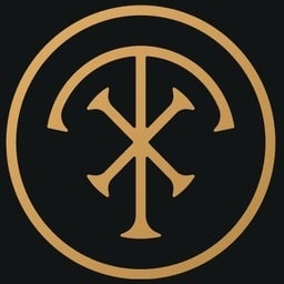 Símbolo circular dourado com um monograma estilizado em fundo preto