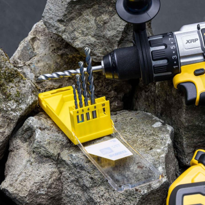 Conjunto de brocas de metal em suporte amarelo junto a furadeira em pedras