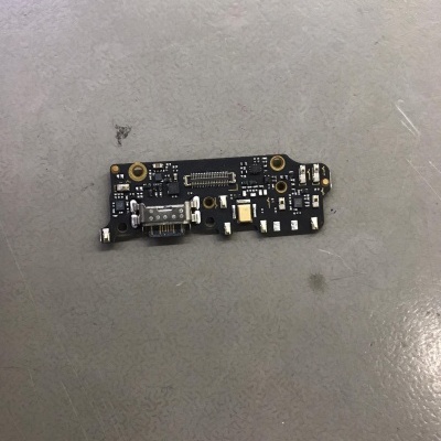 Placa eletrónica preta com conector USB e componentes pequenos sobre superfície cinza