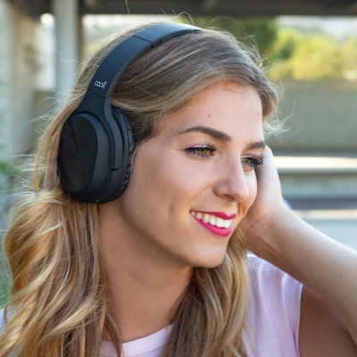 Mulher jovem a usar headphones pretos grandes ao ar livre
