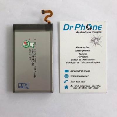 Bateria de smartphone junto a cartão de visita da empresa Dr Phone Assistência Técnica