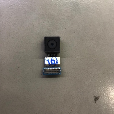 Módulo de câmara preto com conector flexível numa superfície cinzenta