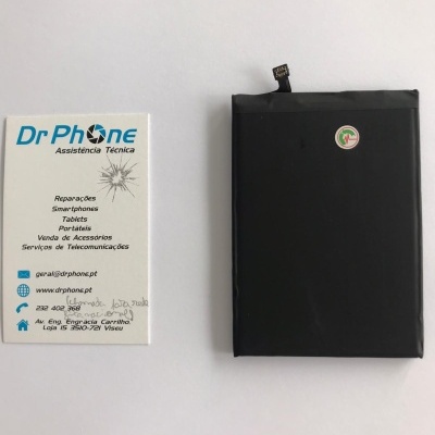 Bateria negra para dispositivo eletrónico ao lado de cartão de visita da empresa Dr Phone