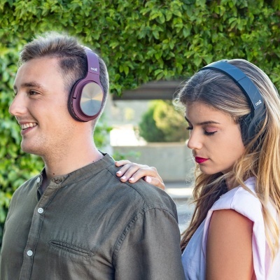 Dois jovens com auscultadores castanhos e pretos junto a uma parede verde
