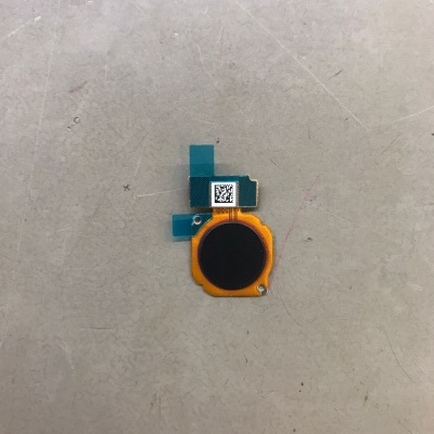 Peça eletrónica pequena com cores preta, amarelo e azul numa superfície cinzenta