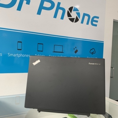 Computador portátil Lenovo preto inclinado em superfície de vidro com cartaz Dr Phone ao fundo