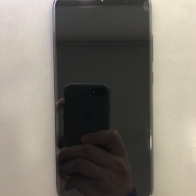 Smartphone com ecrã preto e moldura cinzenta em superfície branca