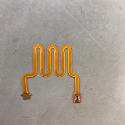 Cabo flexível amarelo com padrão ondulado e componentes eletrónicos nas extremidades