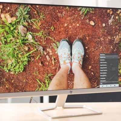 Ecrã de computador exibindo imagem de pés com sapatilhas sobre terra vermelha com vegetação