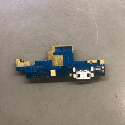 Placa eletrónica azul com componentes dourados e conector branco sobre superfície cinzenta