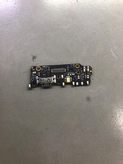 Placa eletrónica preta com conector USB e componentes pequenos sobre superfície cinza