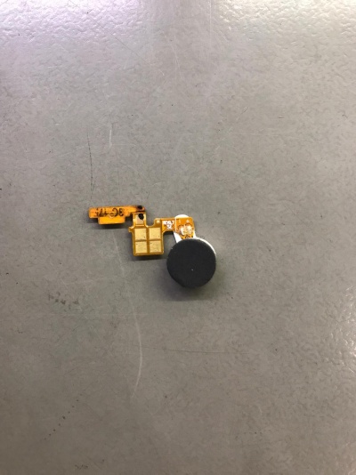 Componente eletrónico pequeno com parte circular preta em fundo cinzento