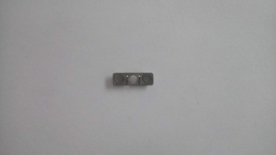 Peça metálica retangular com três orifícios sobre fundo branco